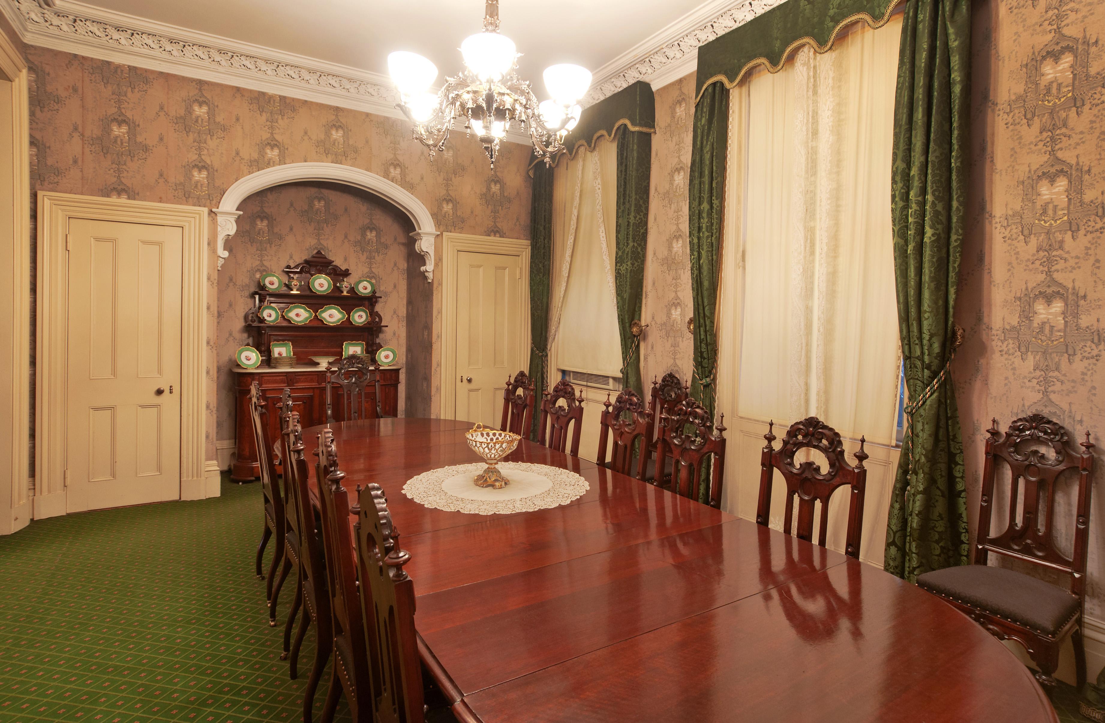 A Victorian-era dining room with a large wooden table.