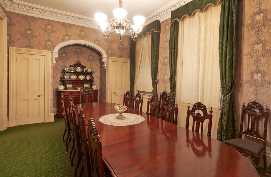 A Victorian-era dining room with a large wooden table.