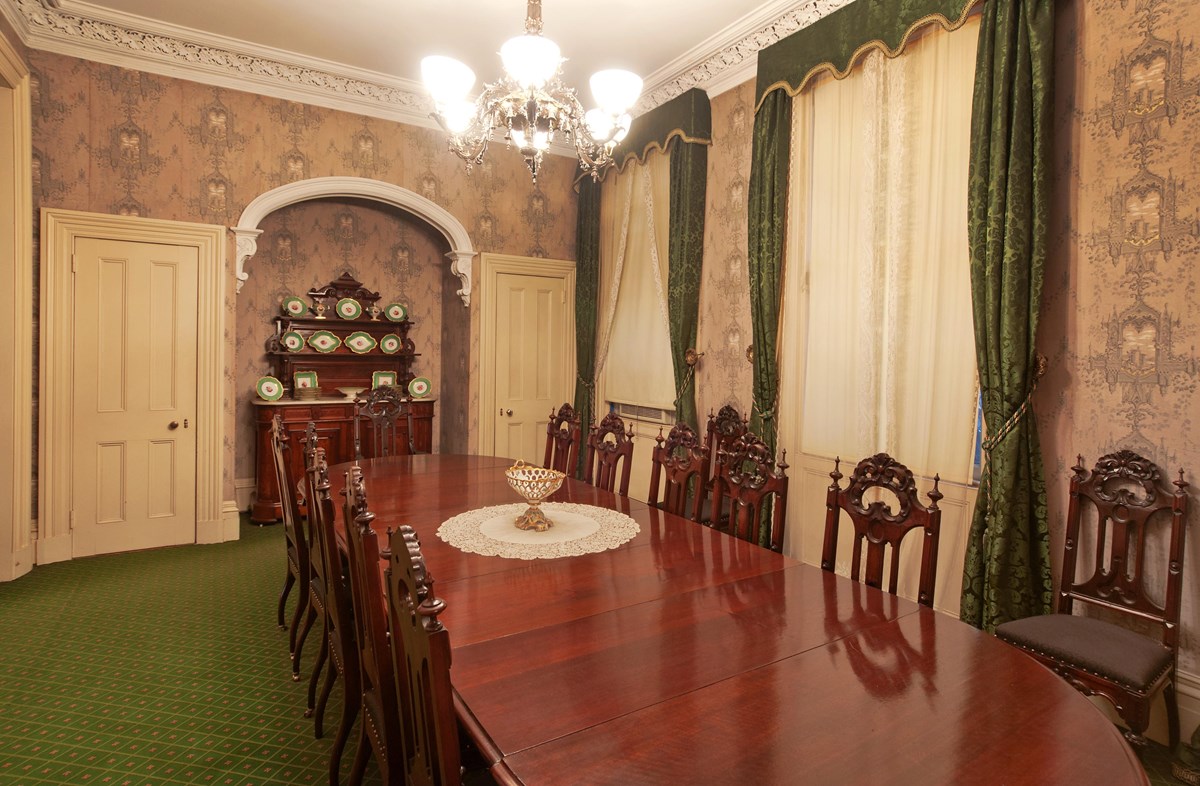 A Victorian-era dining room with a large wooden table.