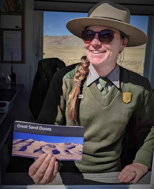 A ranger greets a visitor at the entrance station with a park brochure