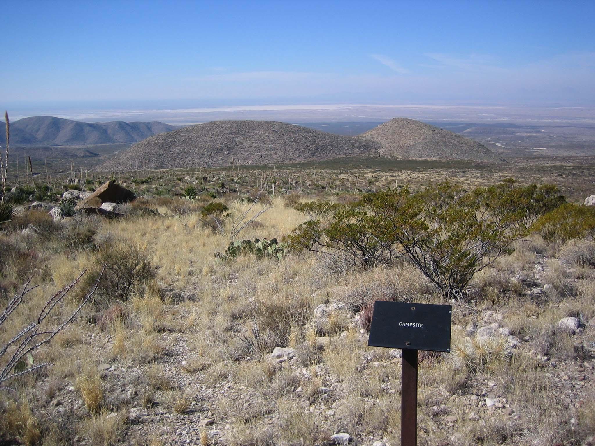 A metal sign marking the camping area rises above the desert landscape.