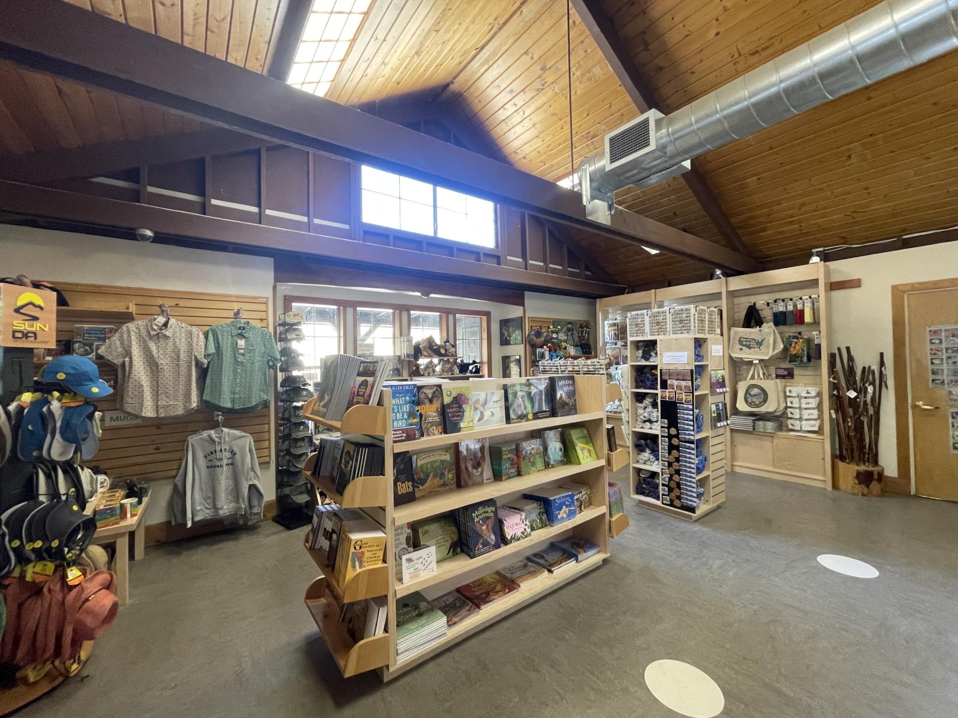 Books, clothing, hiking sticks, hats, and magnets seen from inside a park store.