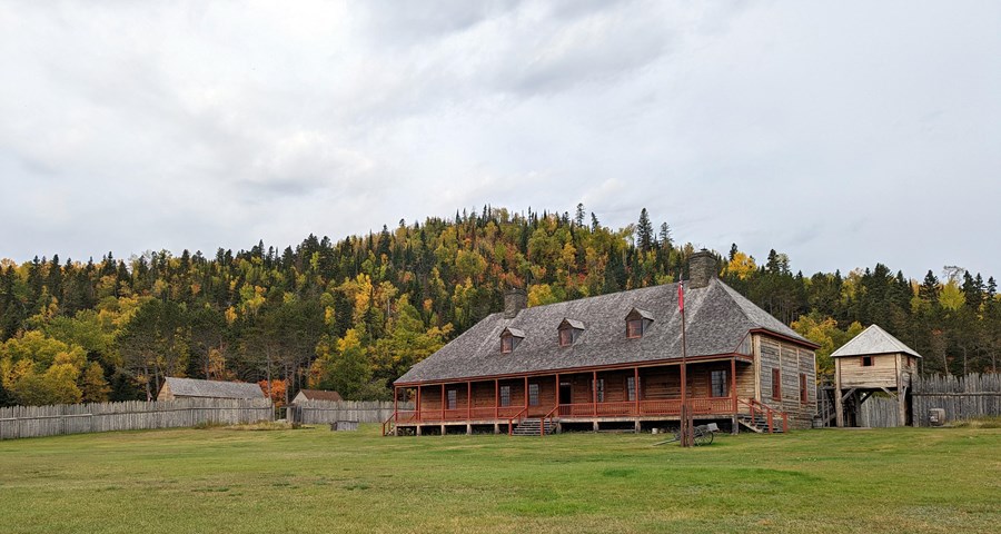 Historic buildings with a lawn in the foreground and hill in fall colors behind.