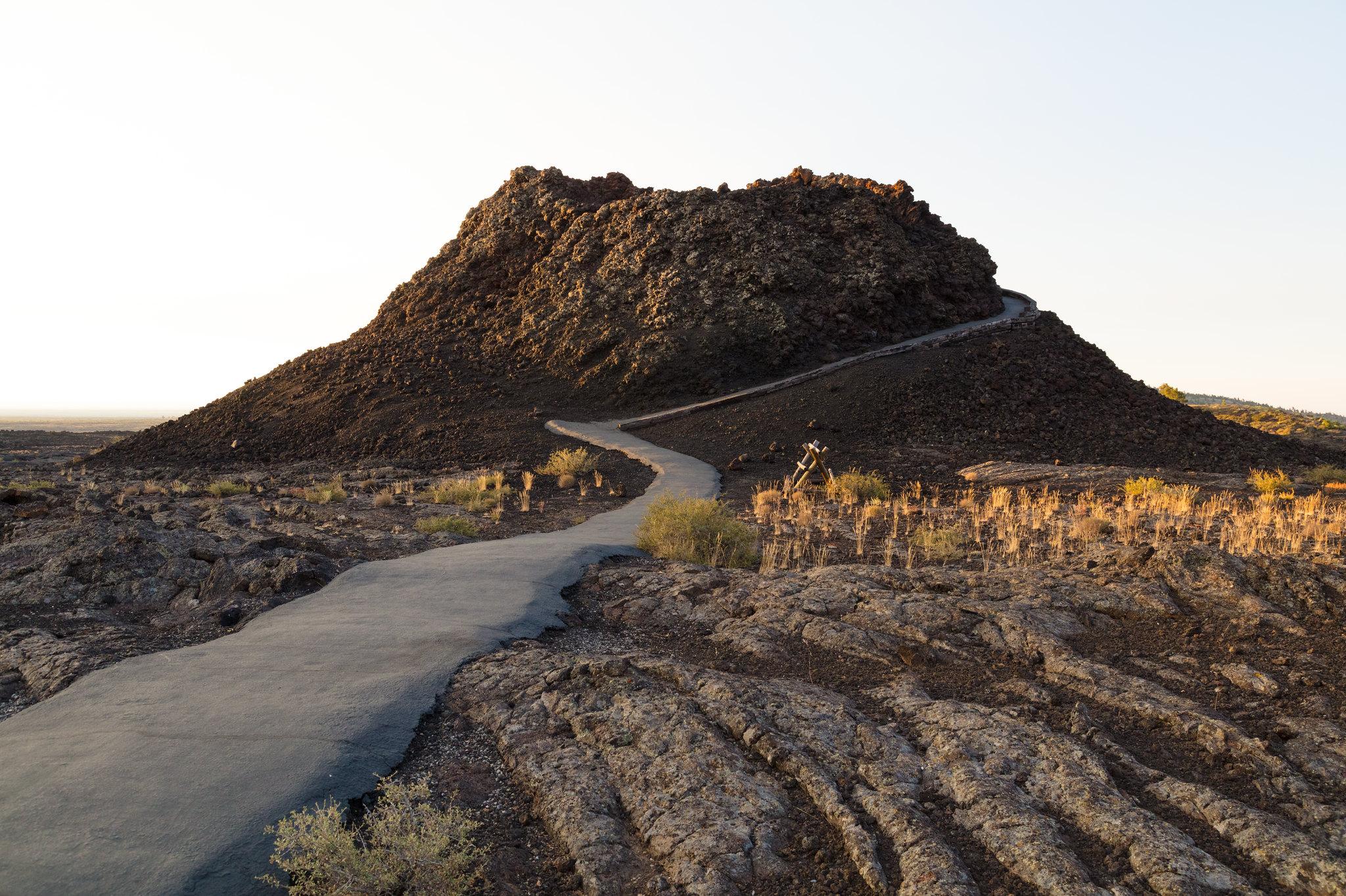 A paved trail winds up around the side of a spatter cone.
