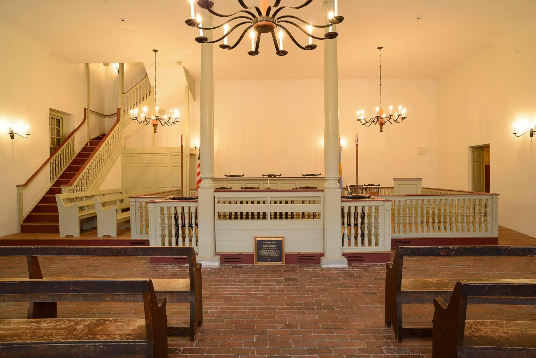 Pews line the side of the room leading to the English style court room.