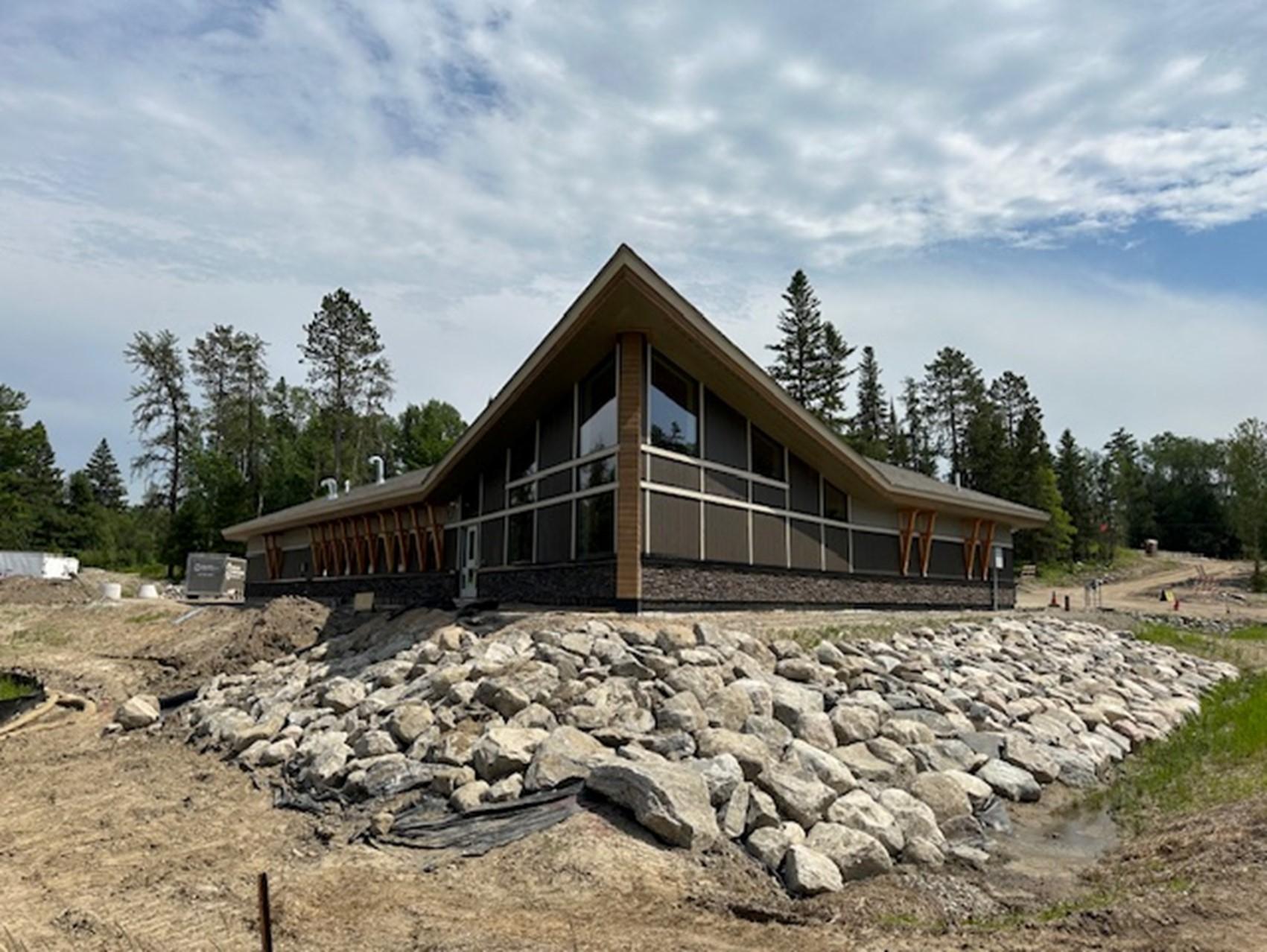 Photograph of building surrounded by landscaping boulders with a blue partly cloudy sky.