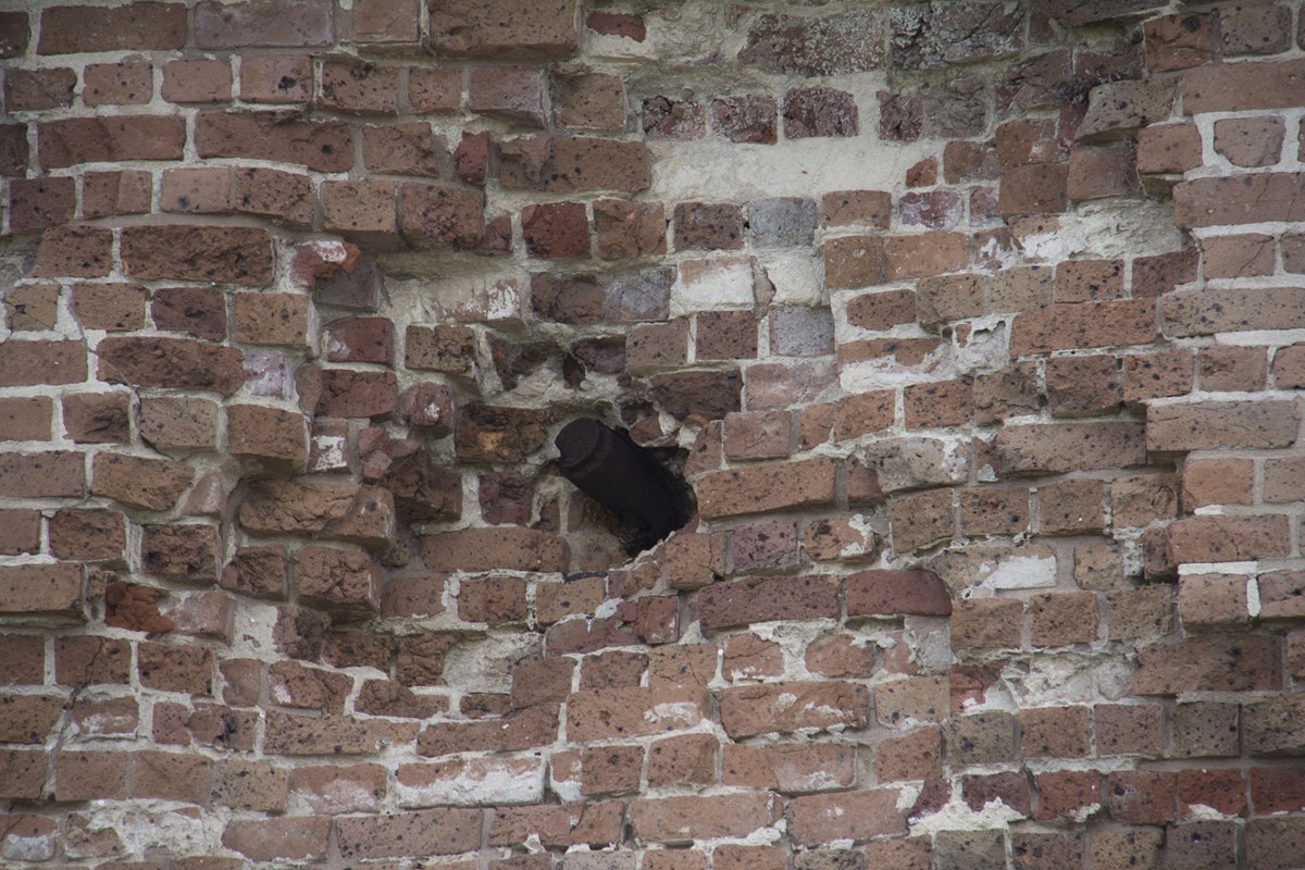 Unexploded artillery shell embedded into a brick wall.