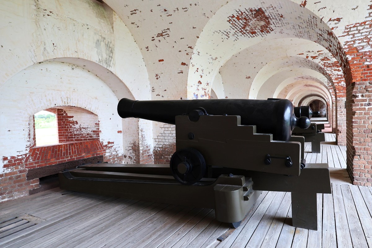 A large cannon set up to fire outside of a small window.