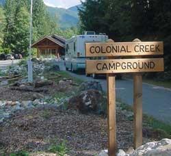 Wooden campground sign in front of a cabin.