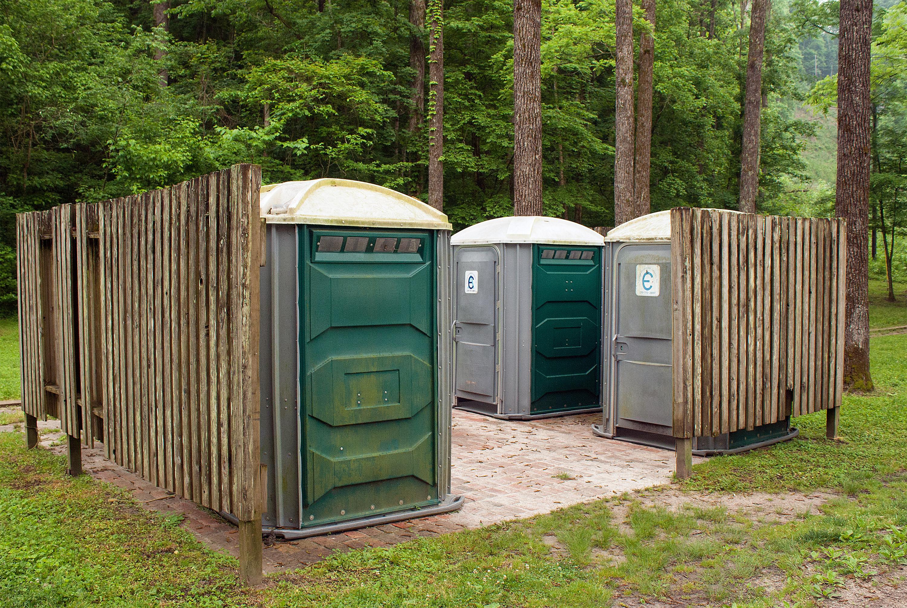 A wooden enclosure containing portable toilet facilities.