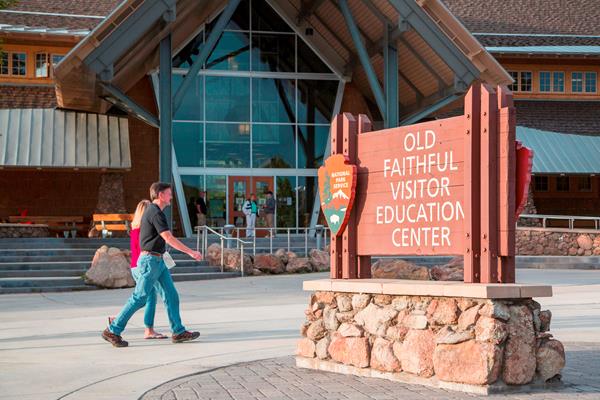 Visitors walk in front of an entrance to Old Faithful Visitor Education Center.