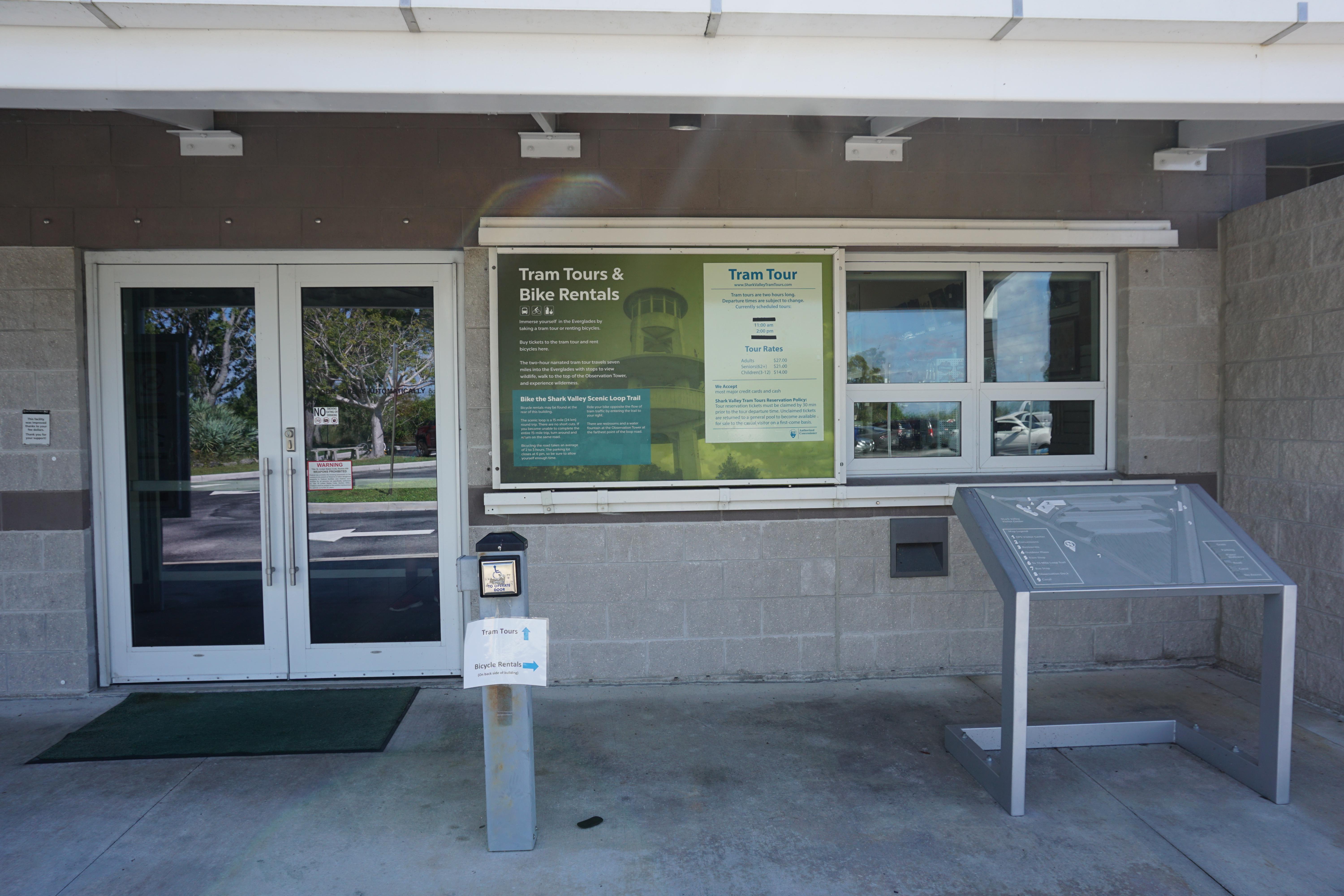 The front doors to the Shark Valley Visitor Center with a wayside exhibit off to the side