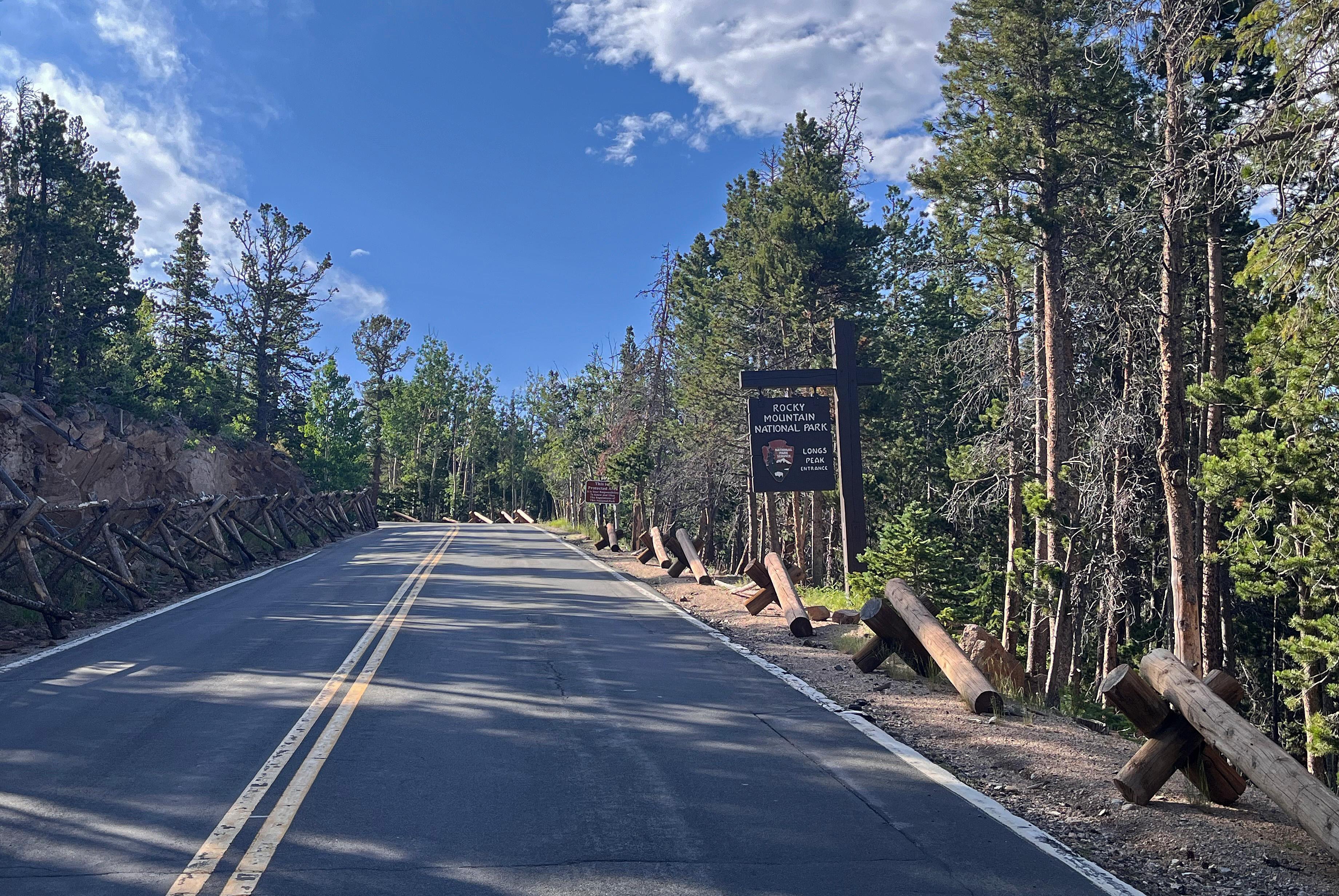 View of the Longs Peak Entrance Sign along a paved road to Longs Peak Trailhead and Campground