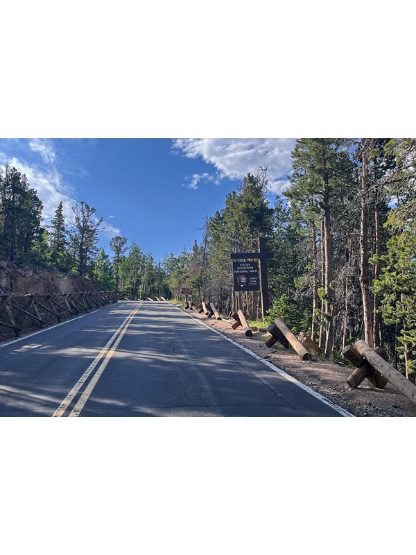 View of the Longs Peak Entrance Sign along a paved road to Longs Peak Trailhead and Campground