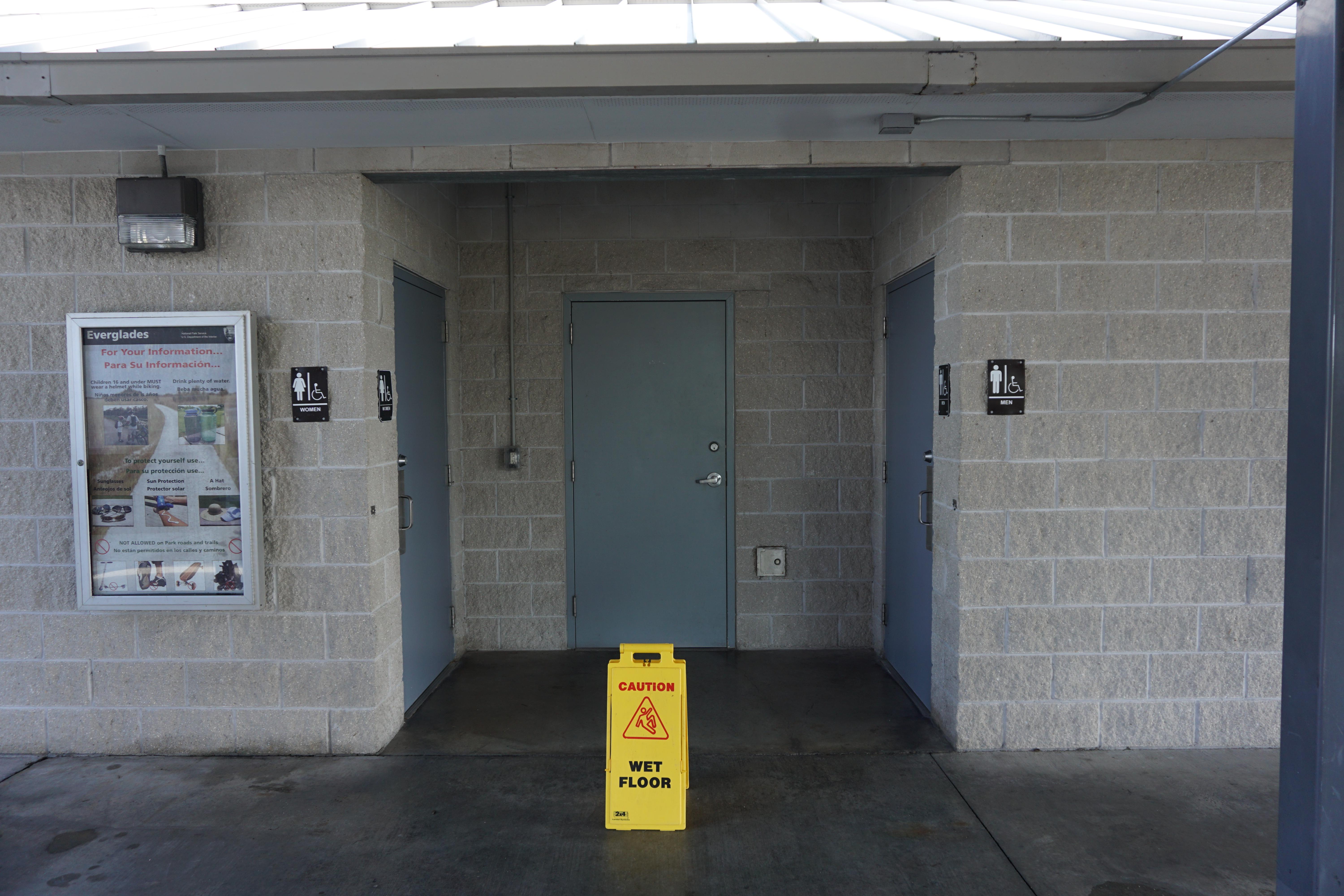 Men's and women's restrooms with a yellow Wet Floor Sign displayed
