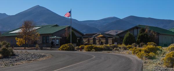 Tan and green Visitor center with mountains in the background.