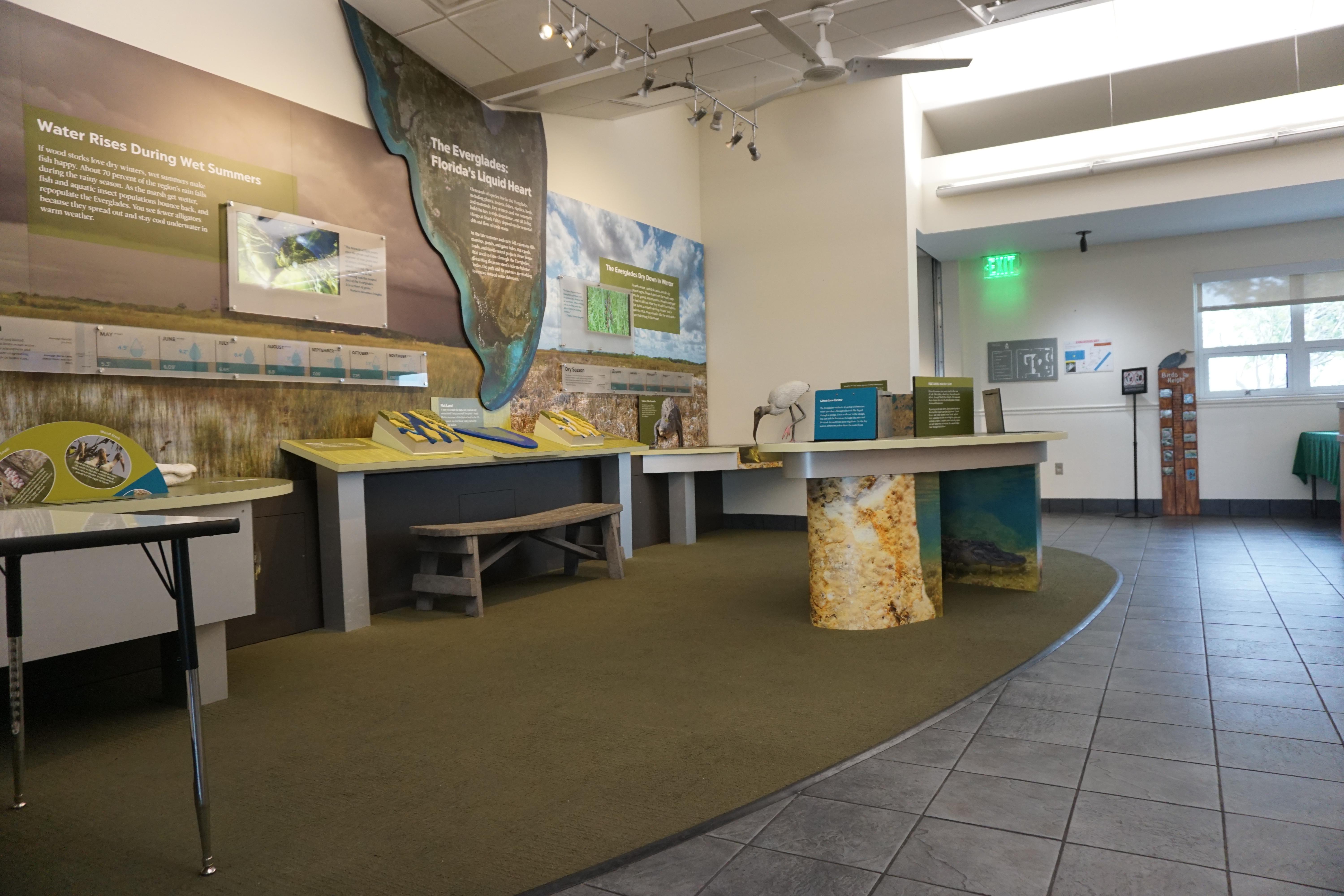 Lit, indoor exhibit area with tables, maps and interpretive panels