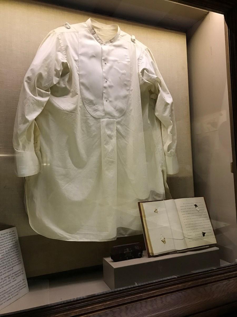 photo of display in museum containing TR's shirt, a speech and eye glasses.