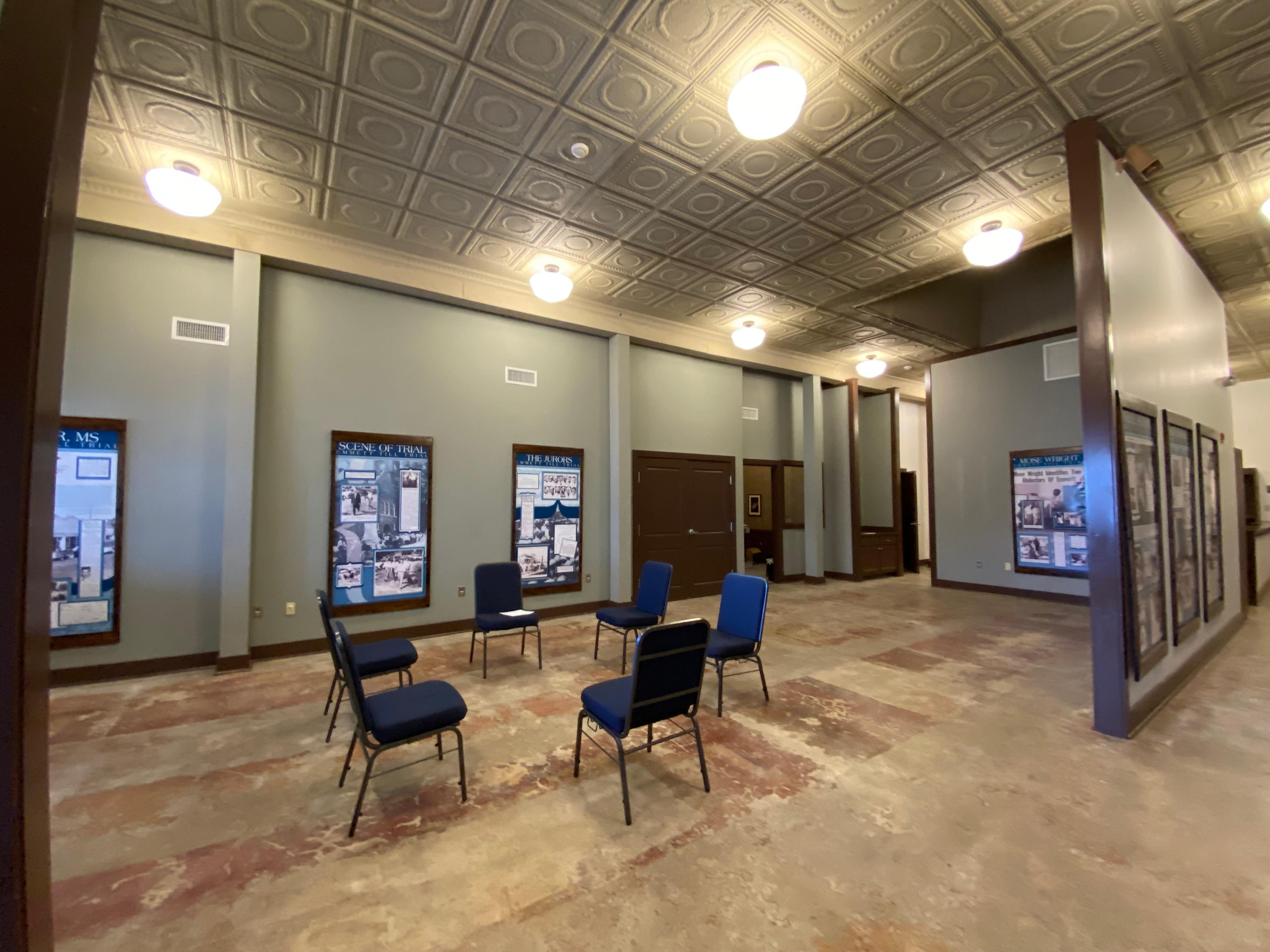 Six chairs sit in a circle in a room that is lined with informational panels.