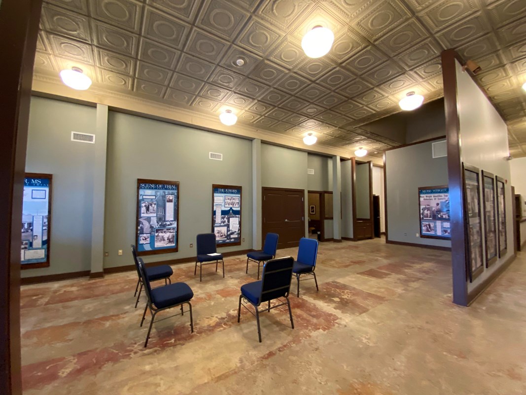Six chairs sit in a circle in a room that is lined with informational panels. 