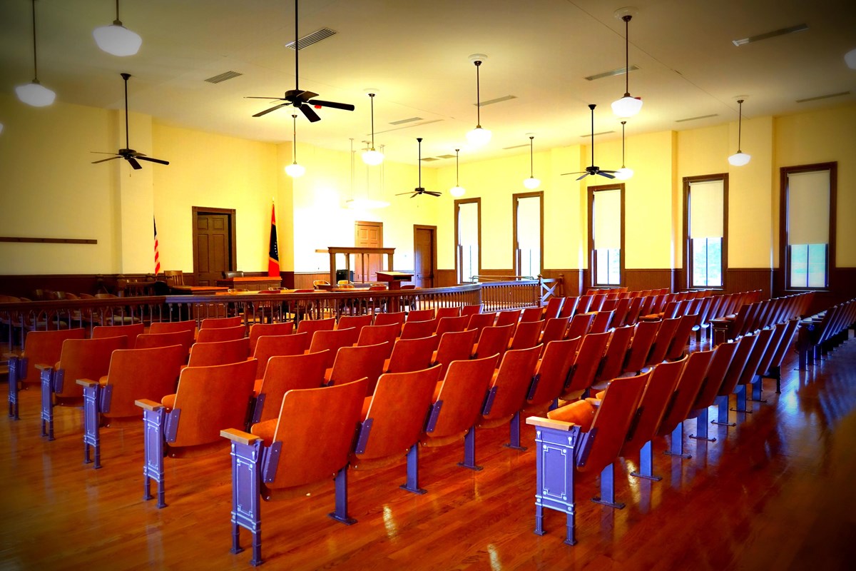 Rows of seats face a bench in an empty courtroom. 