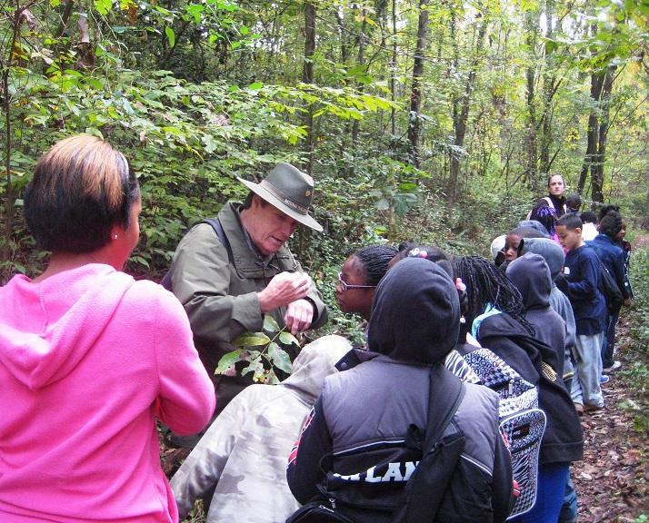 Park ranger showing a group of school children the critter on his arm.