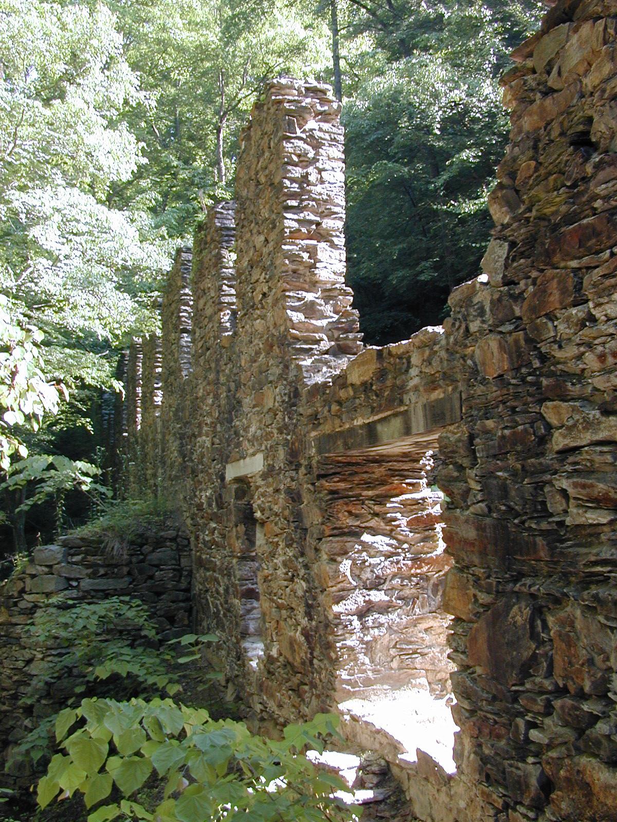 Stone ruins of the Marietta Paper Mill surrounded by lush green vegatation.