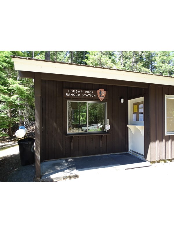 A small brown building with a window for taking questions.