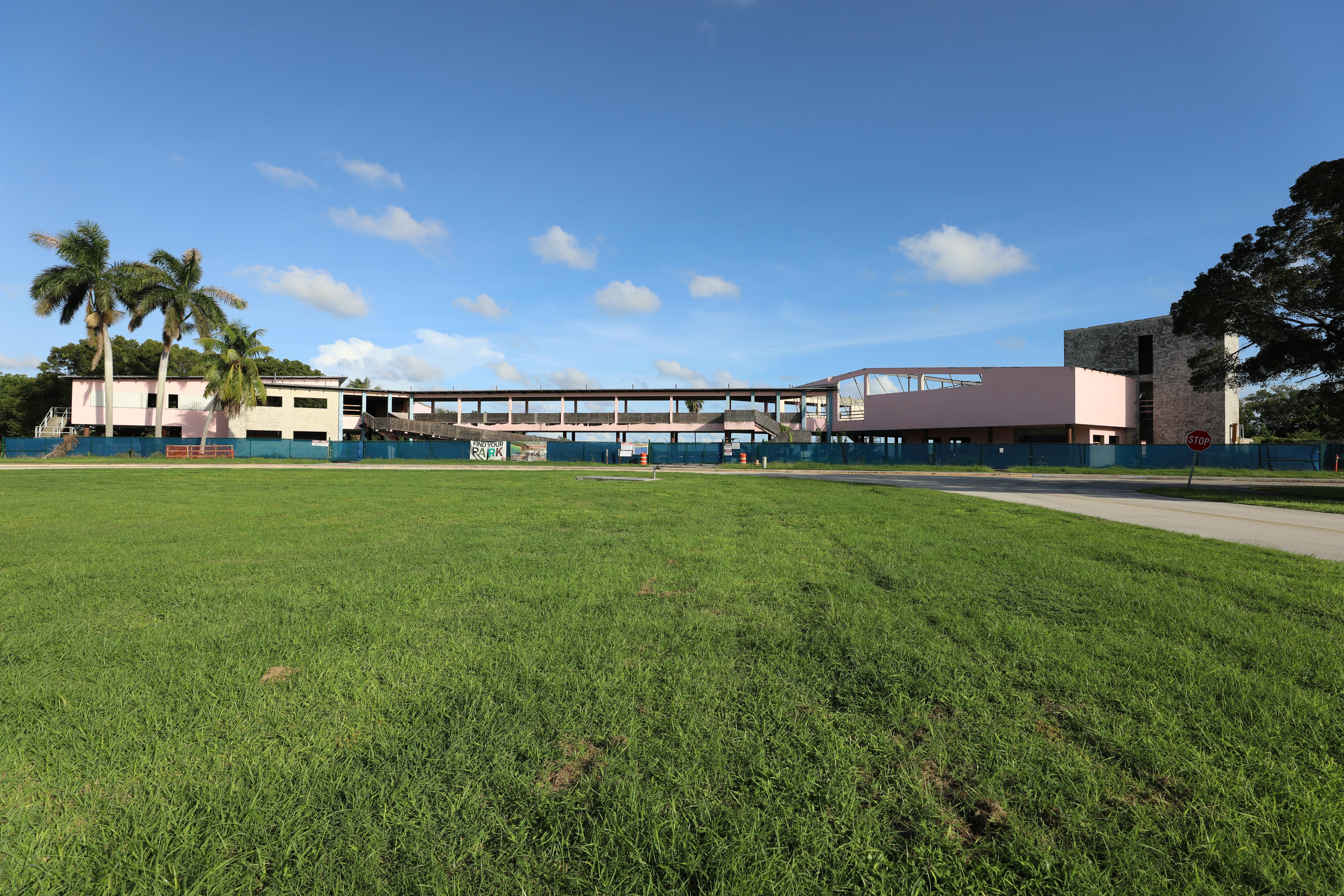 A large green lawn with two pink buildings in the background