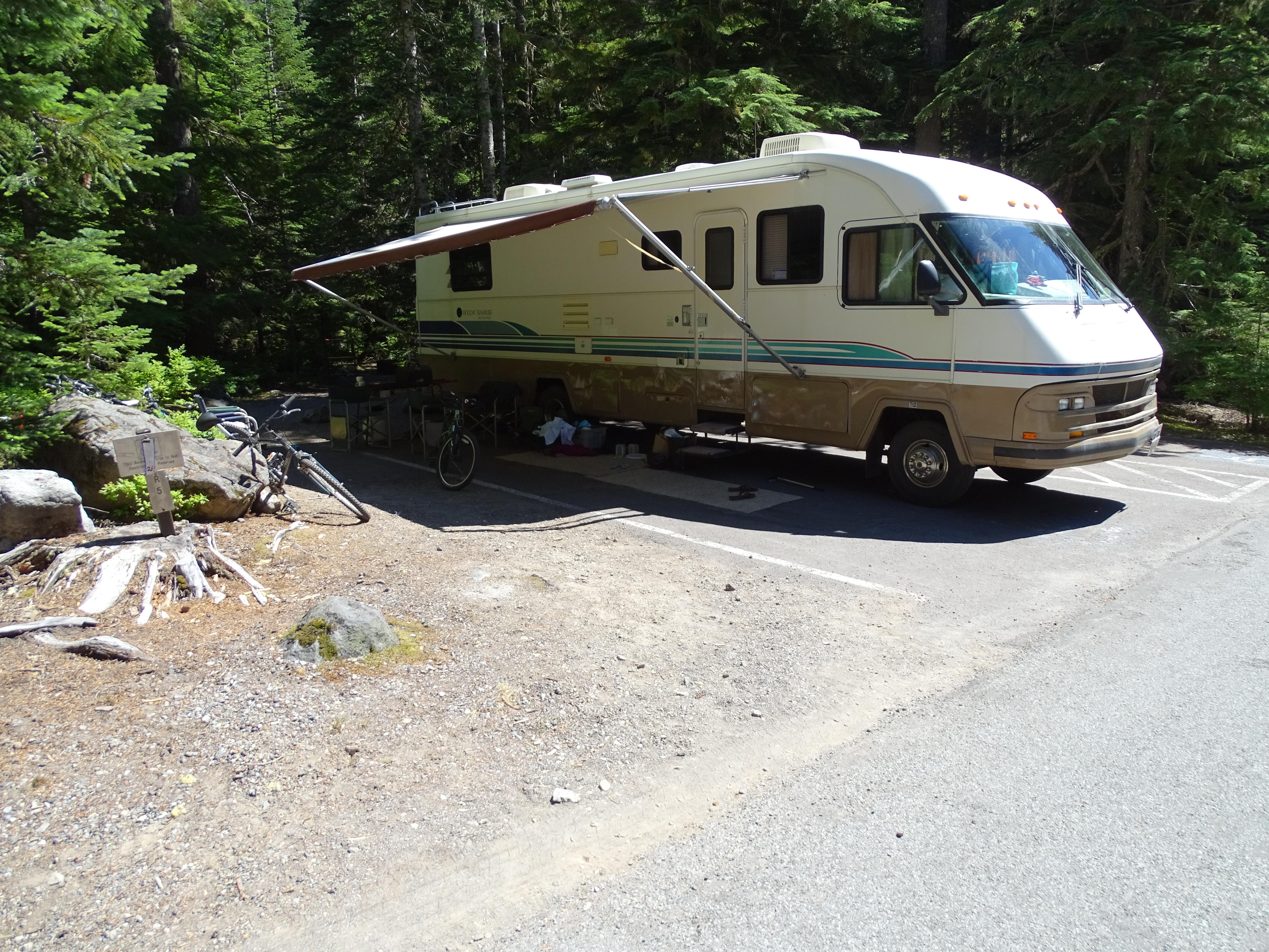 A large white RV in front of thick woods