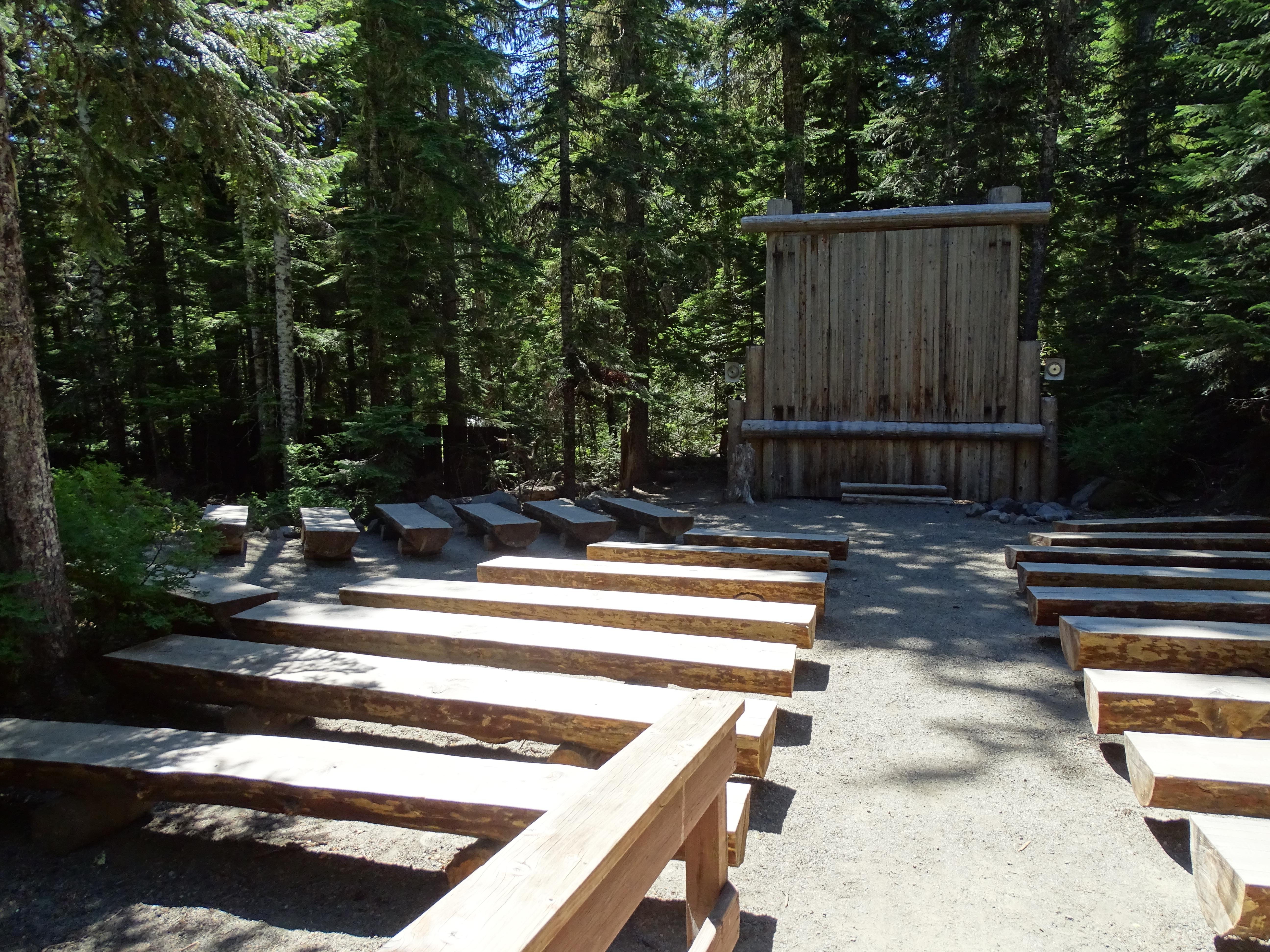 Rows of wooden benches leading up to a screen with wooden panelling