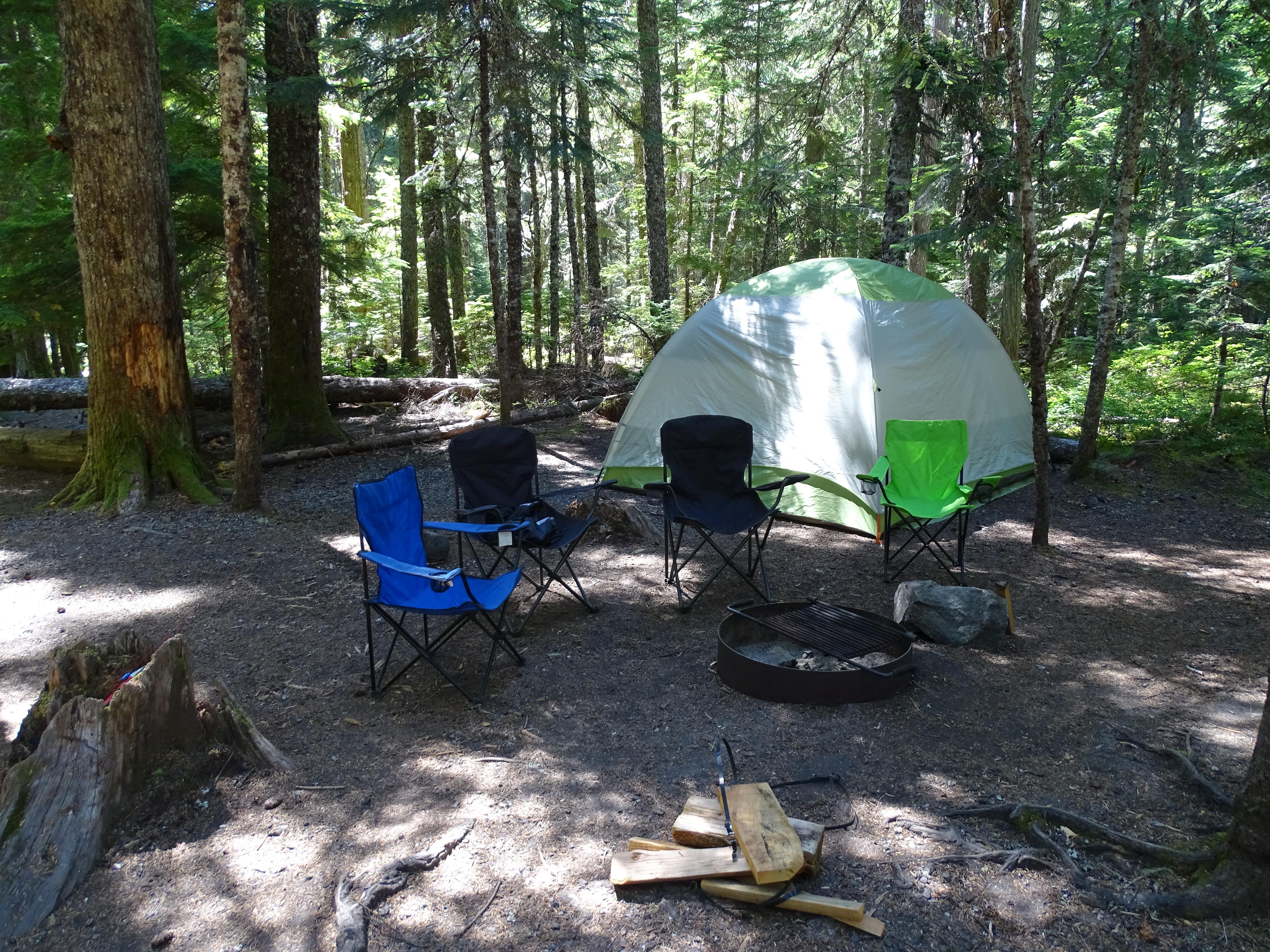 Four fold up chairs in front of a large tent.