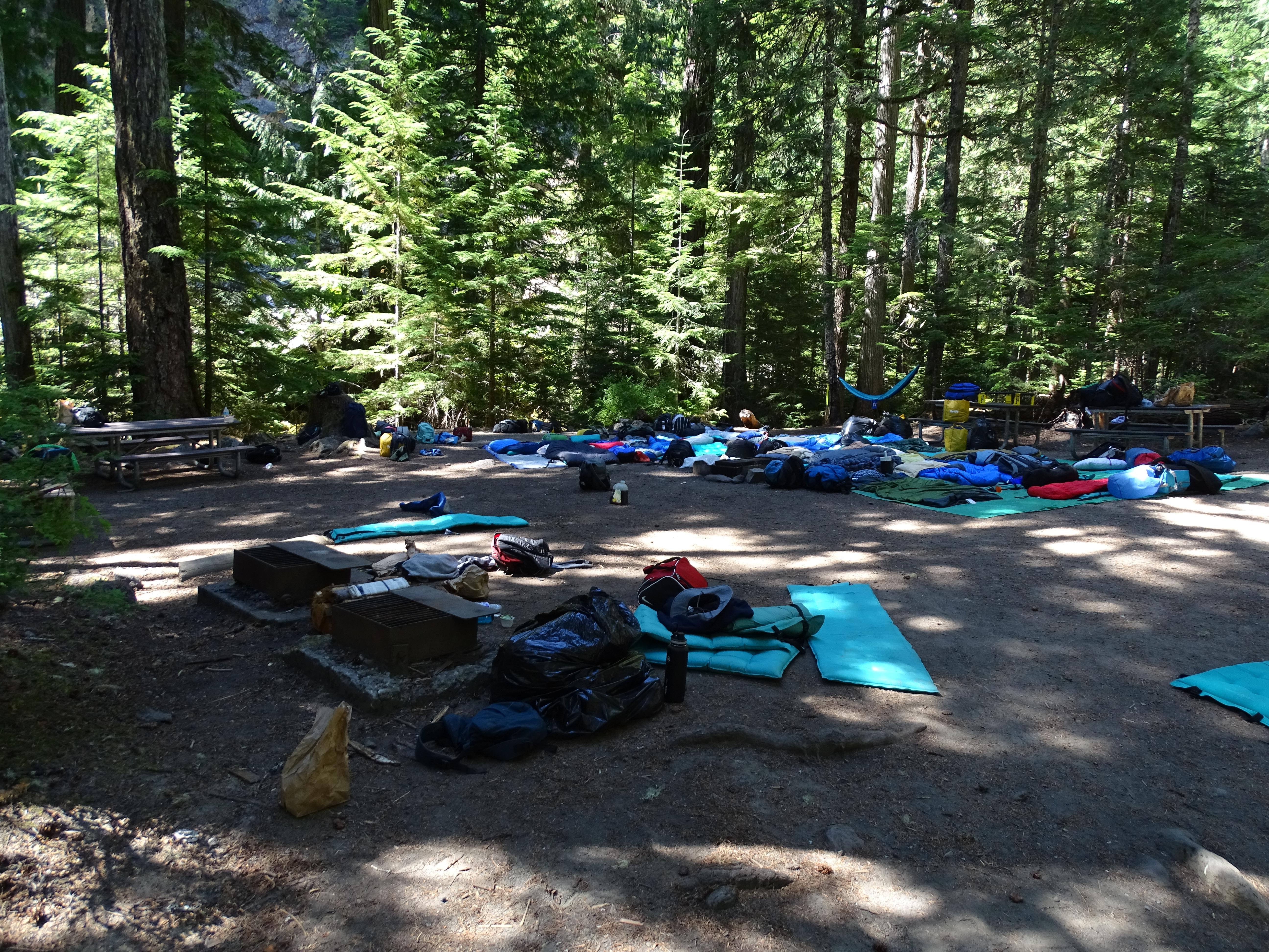 A large open space with scattered sleeping bags and camp materials