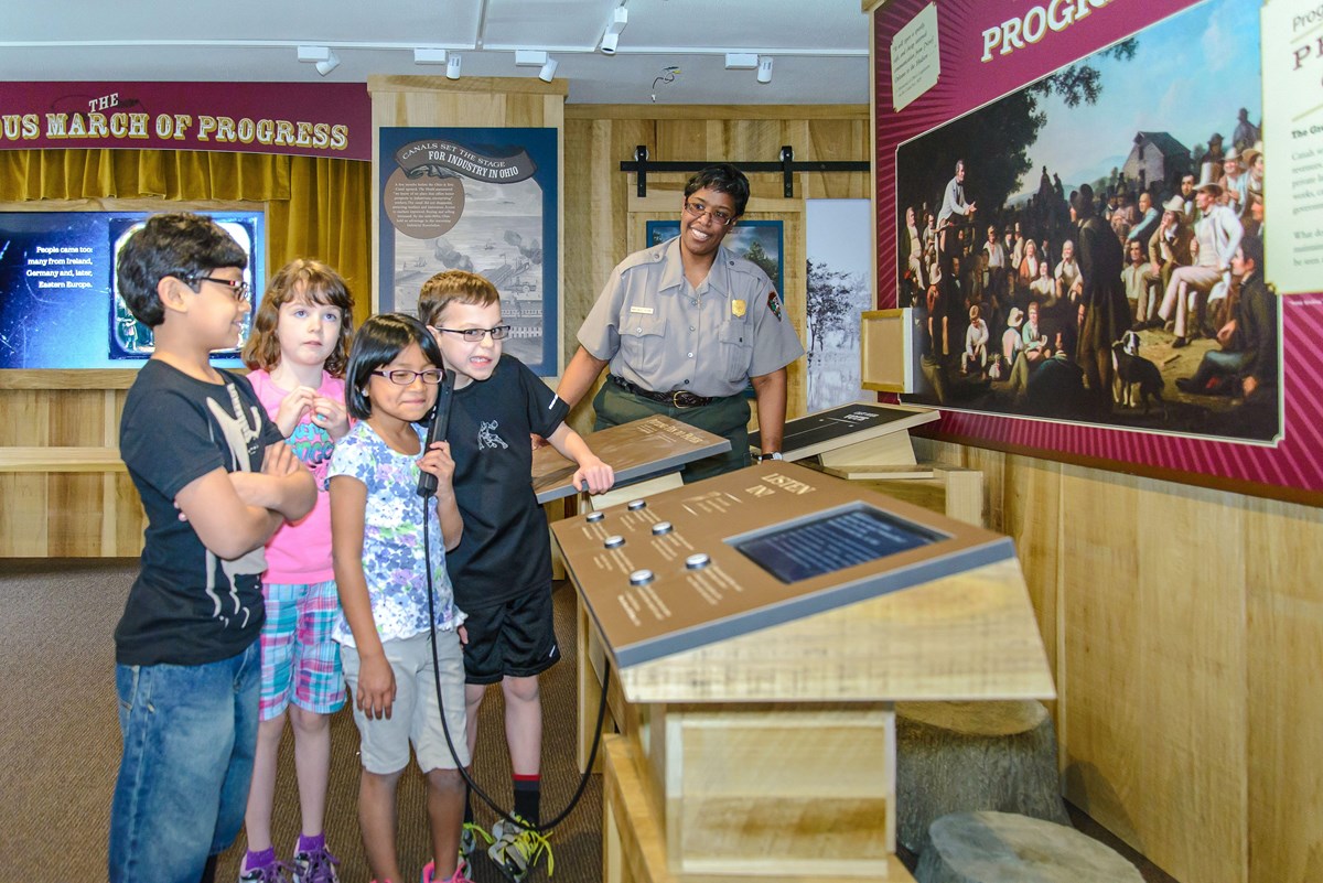 Four children explore an interactive exhibit with a park ranger.