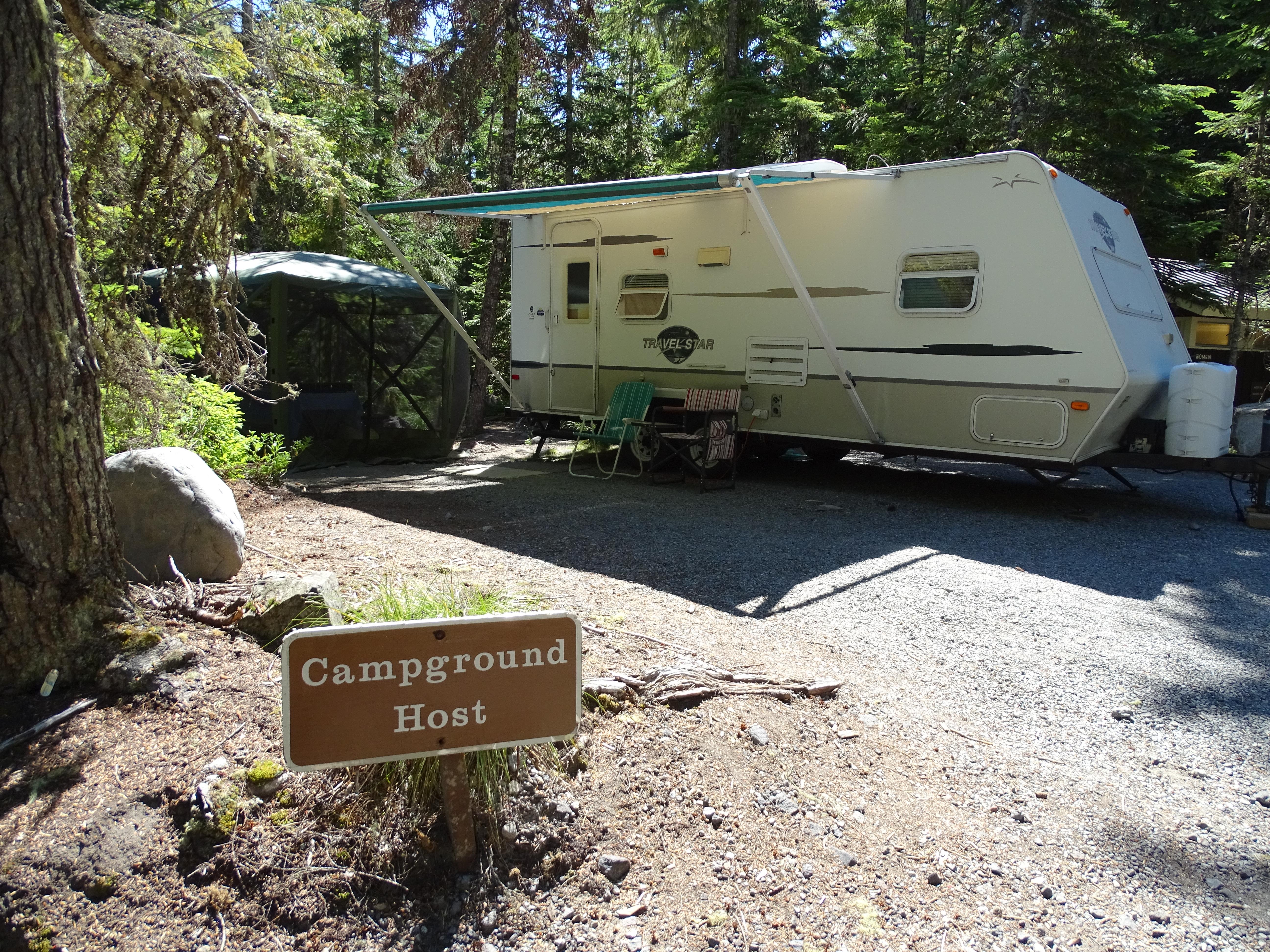 A white RV trailer nestled in the woods.