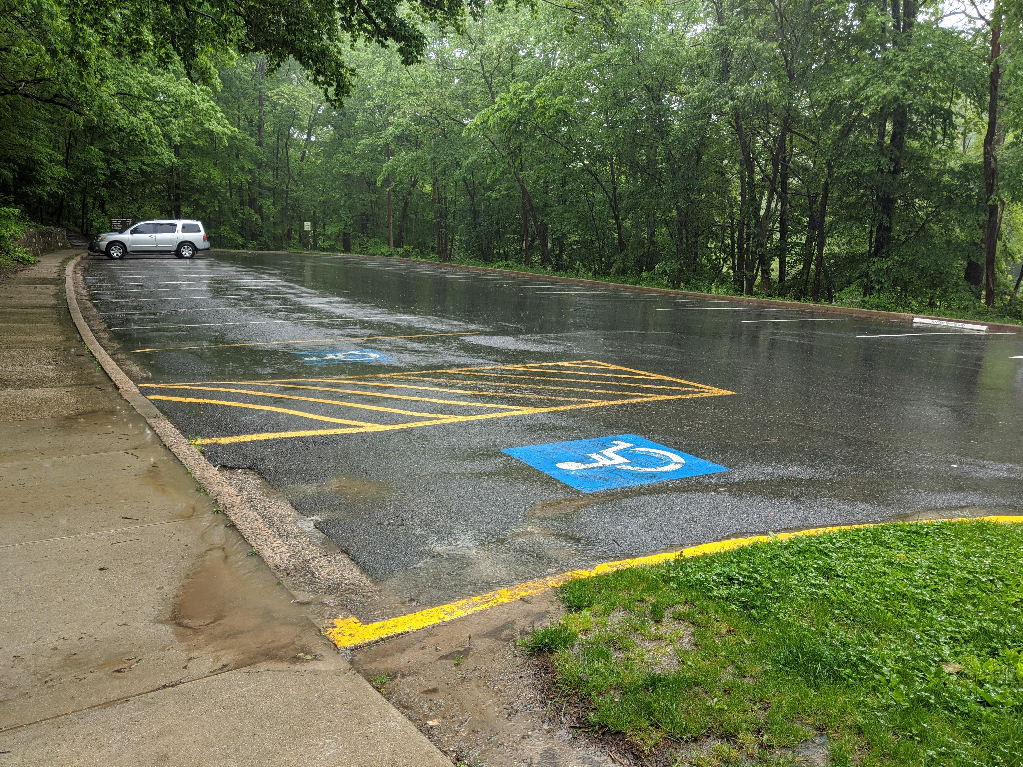 Large Asphalt Parking Area with Handicapped Parking Spaces Closest In Image. 