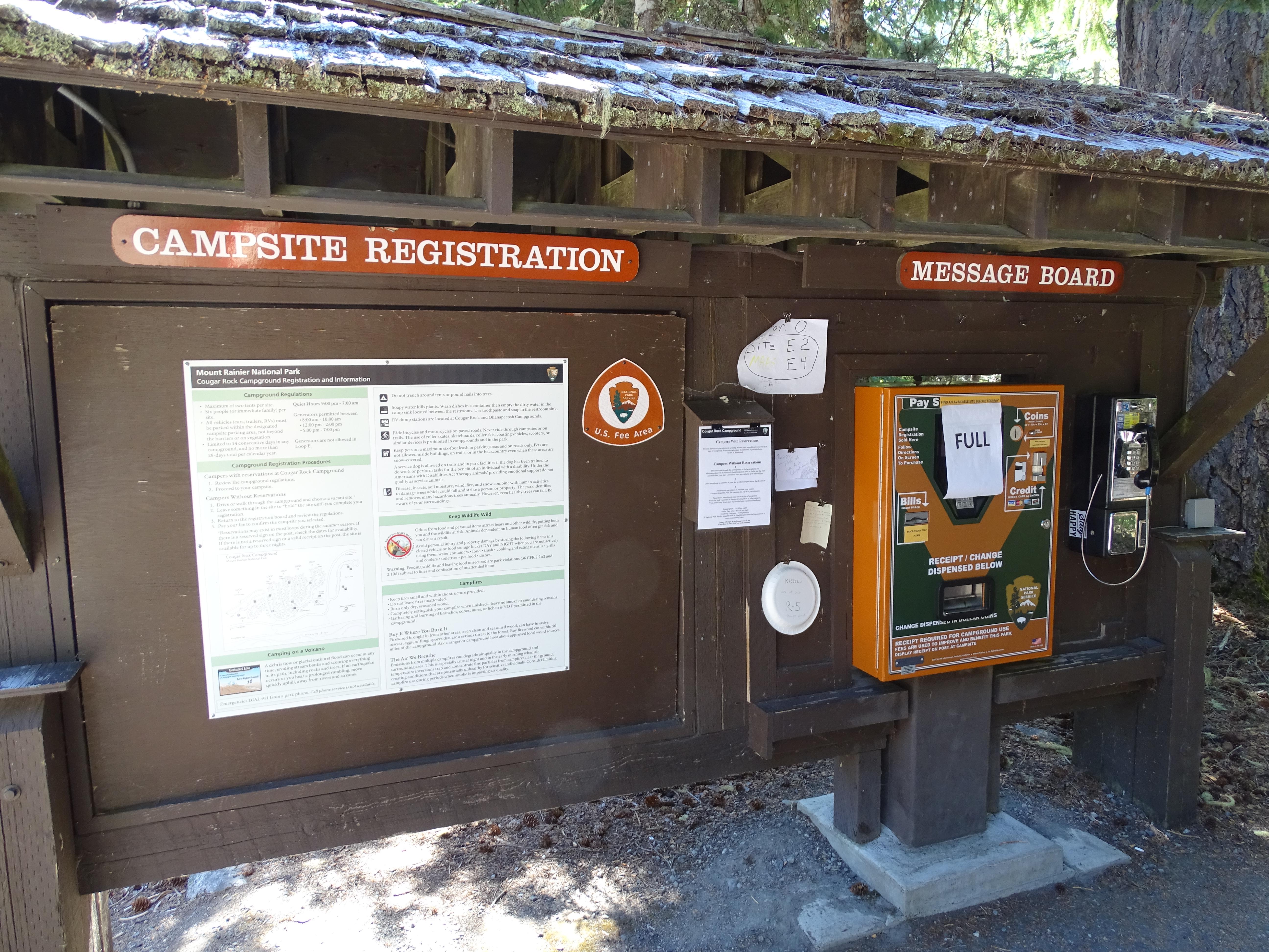 A broad message board with a pay phone.