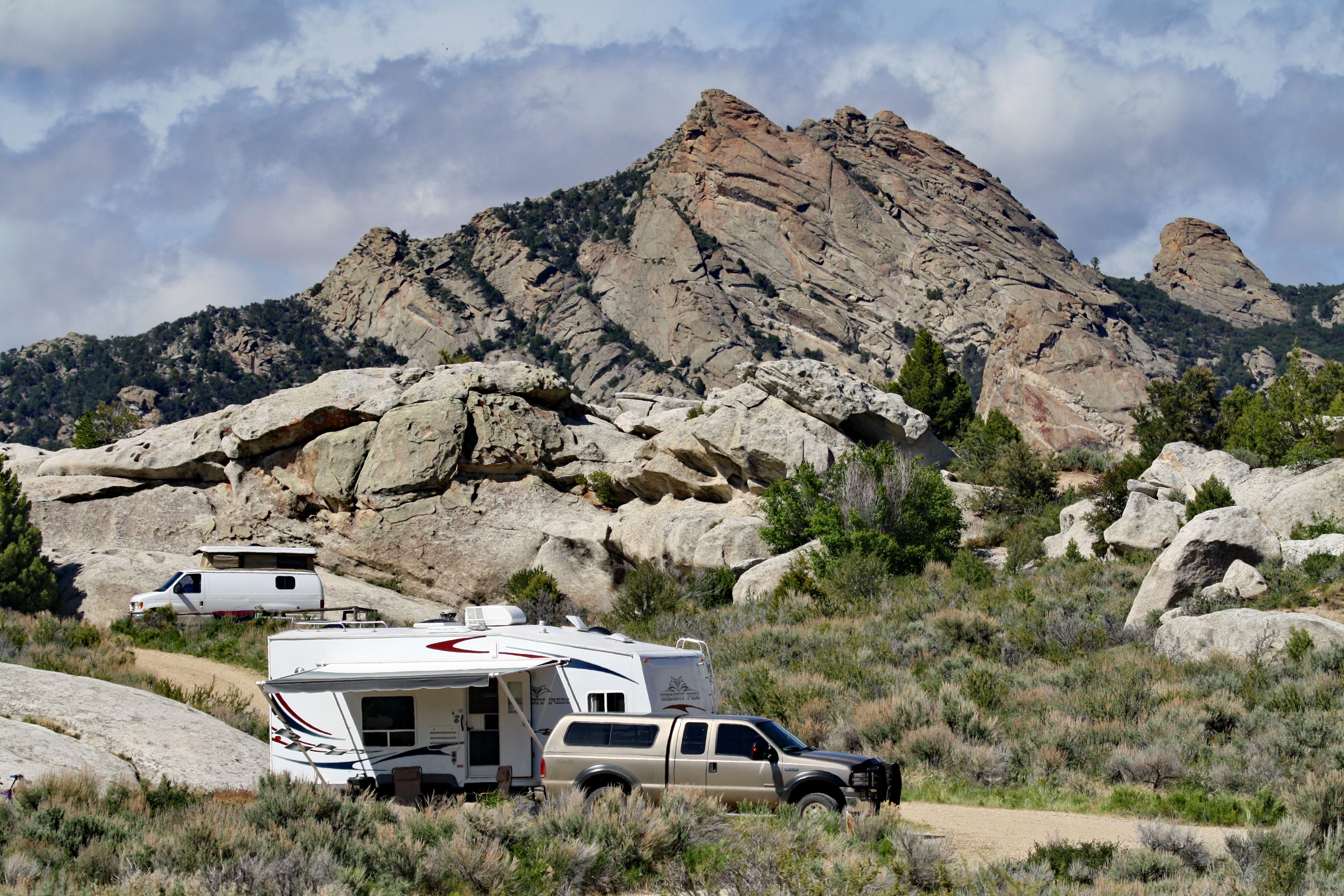 A camp trailer is parked with granite rocks behind