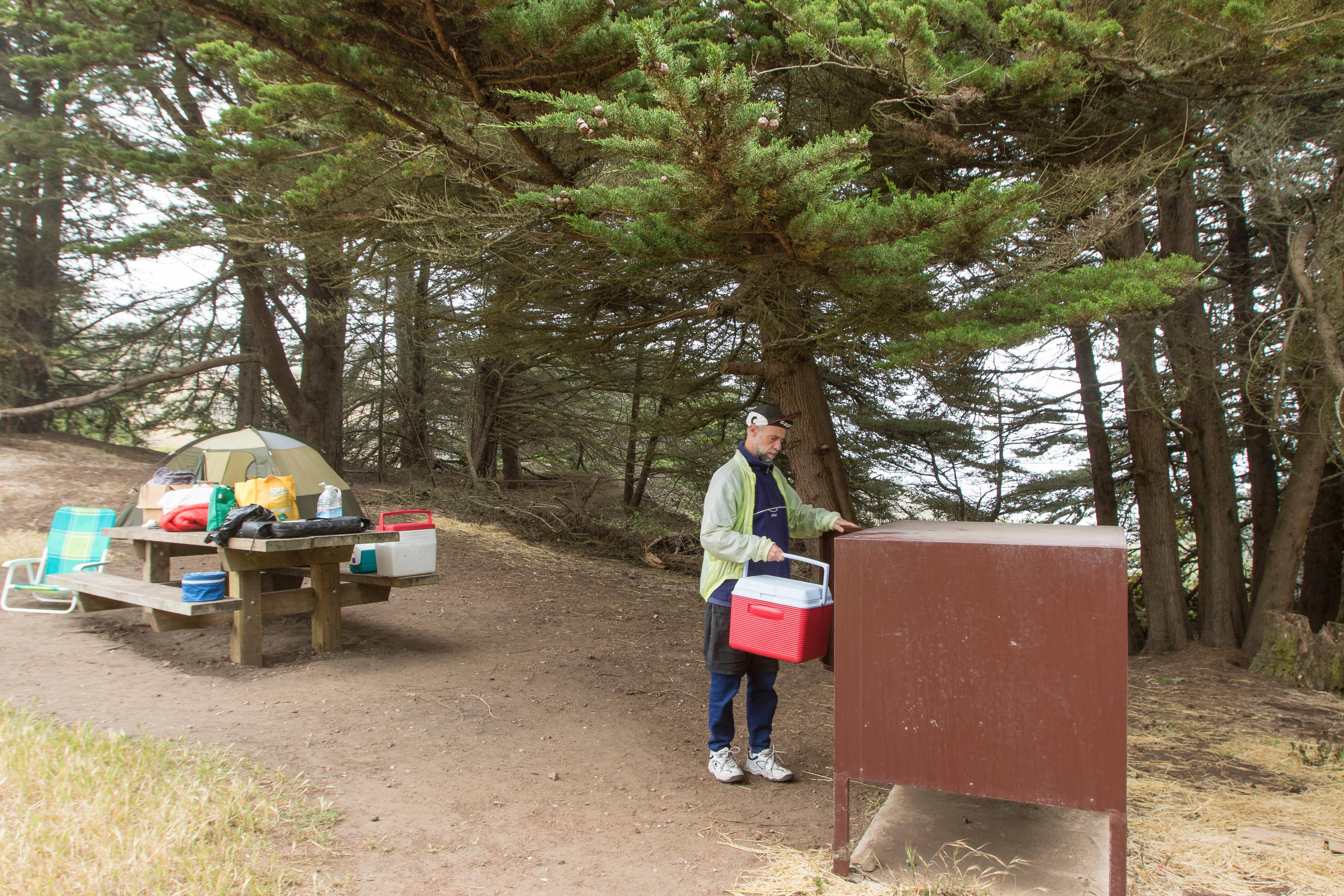 Campers make use of the food storage boxes and picnic tables at the campground.