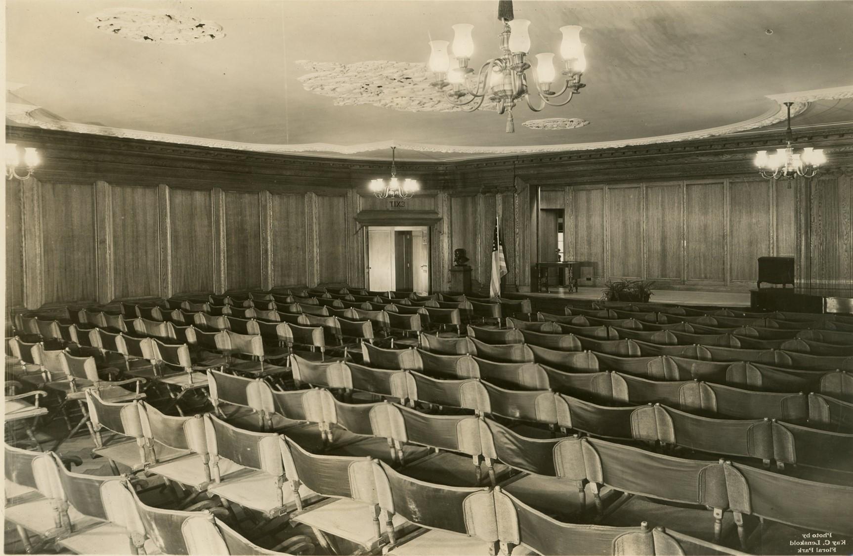 Sepia photograph of auditorium full of chairs in rows