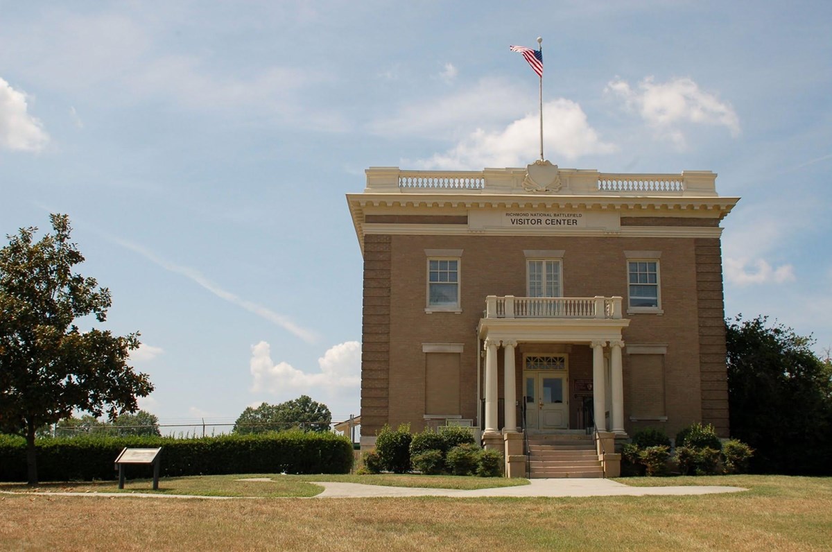 A two story gray brick building and a wooden sign reading "Chimborazo Visitor Center"