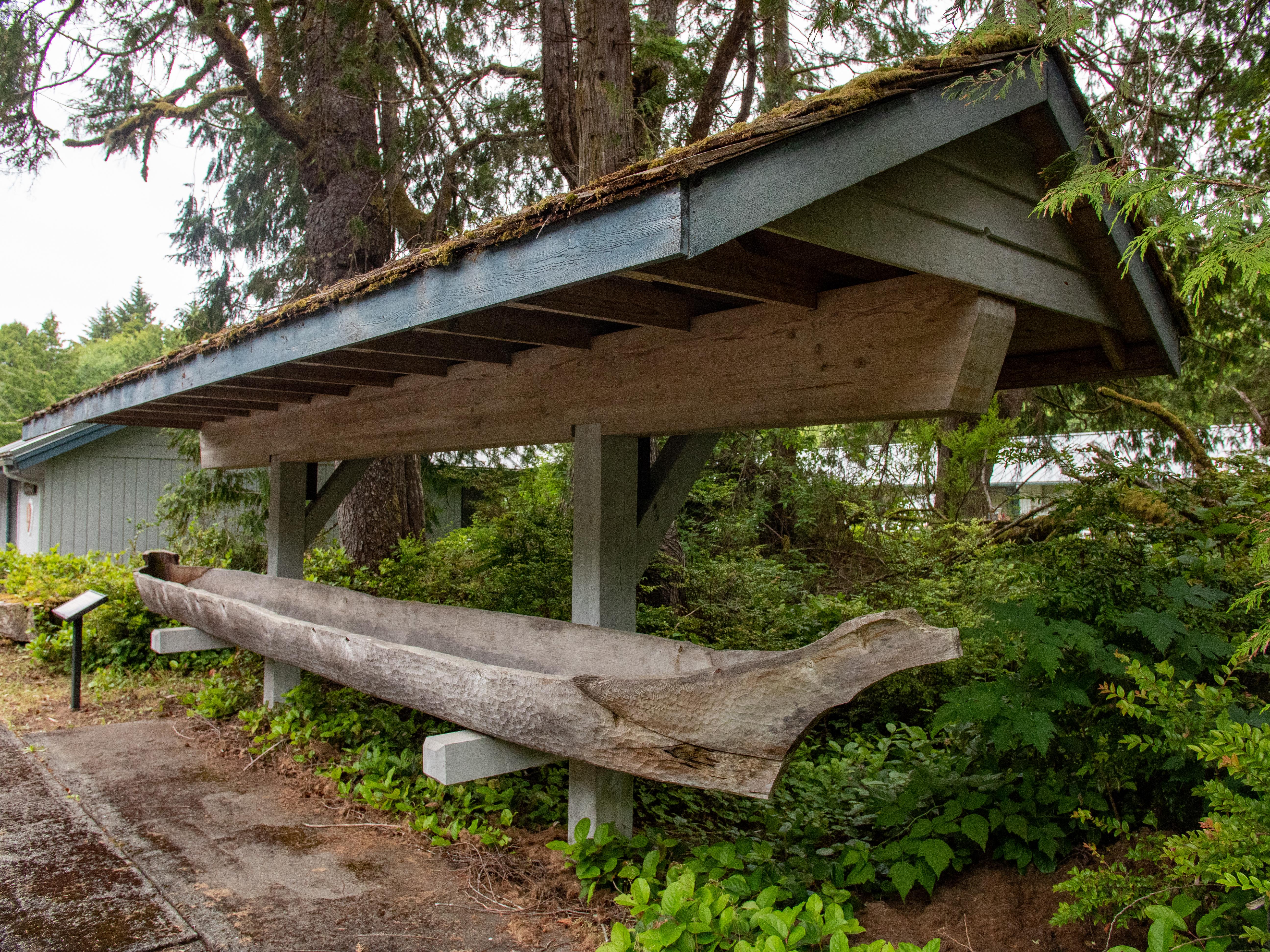 A wooden canoe in an open air, roofed display.