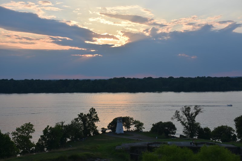 Potomac View a green shoreline with small lighthouse along river at sunset