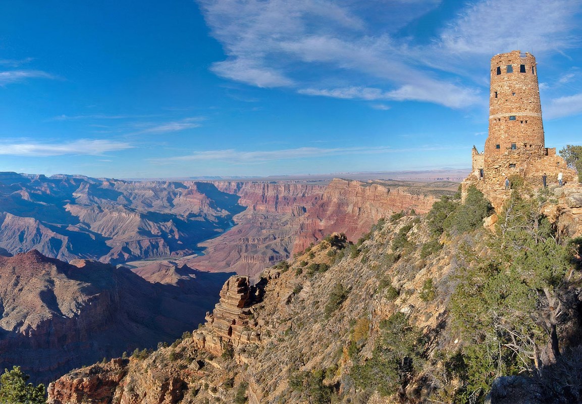 A cylindrical, stone tower, 70 feet (21 m) is on the edge of a vast, mile-deep canyon 