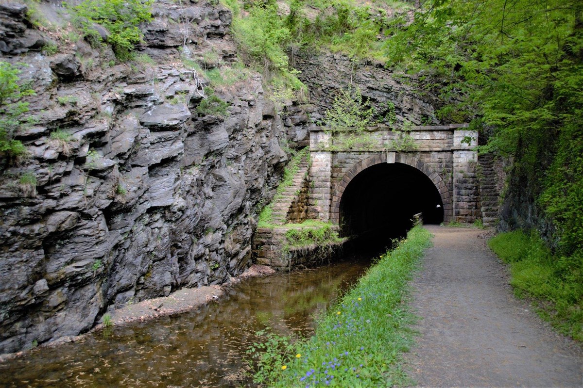 A path leads up to a large stone tunnel carved into a mountain