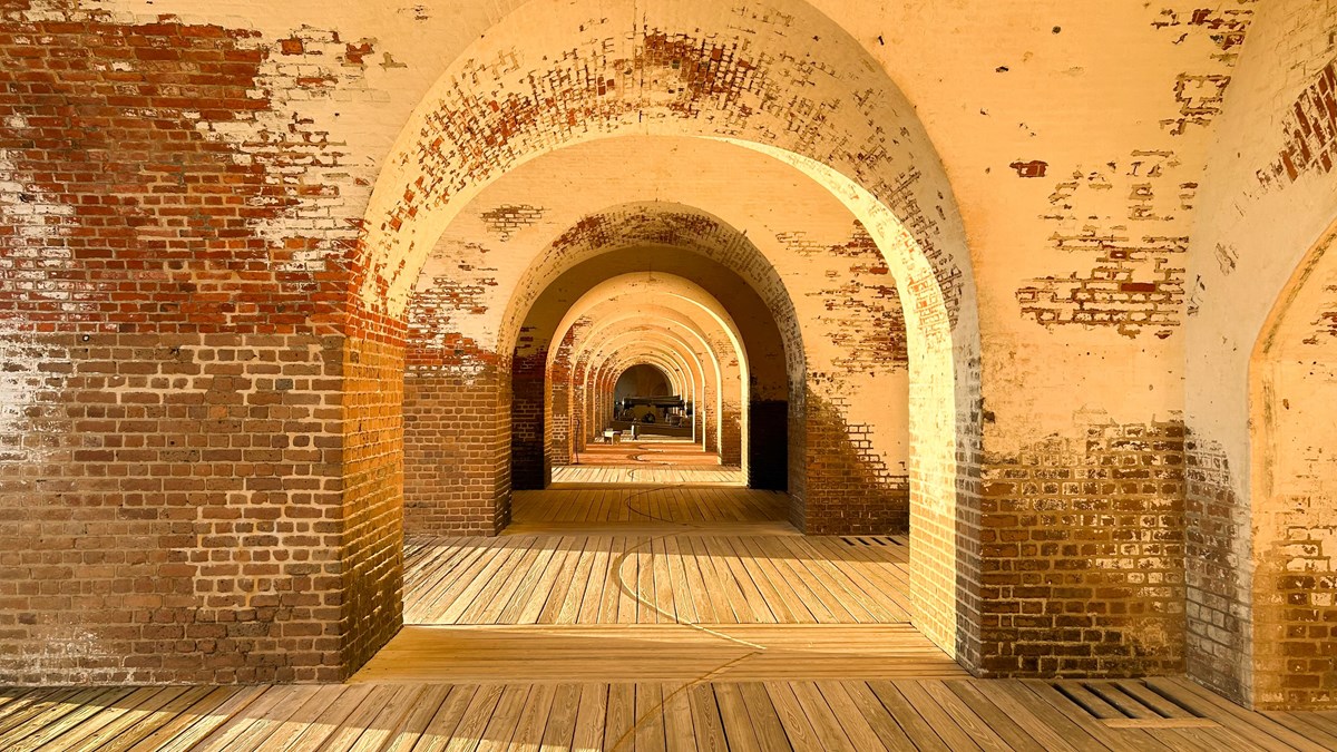 The brick of the fort glow in the late afternoon light. The arches inside the fort reveal a cannon i