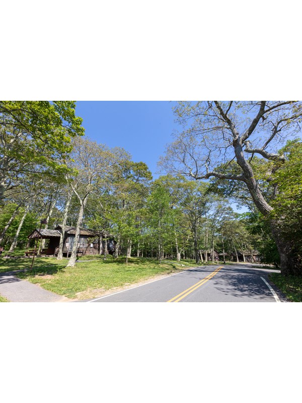 A paved road branches off at the entrance to a campground, with cabins in the distance.