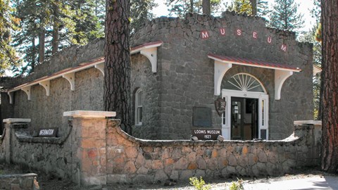 A one-story stone building surrounded by a short stone wall