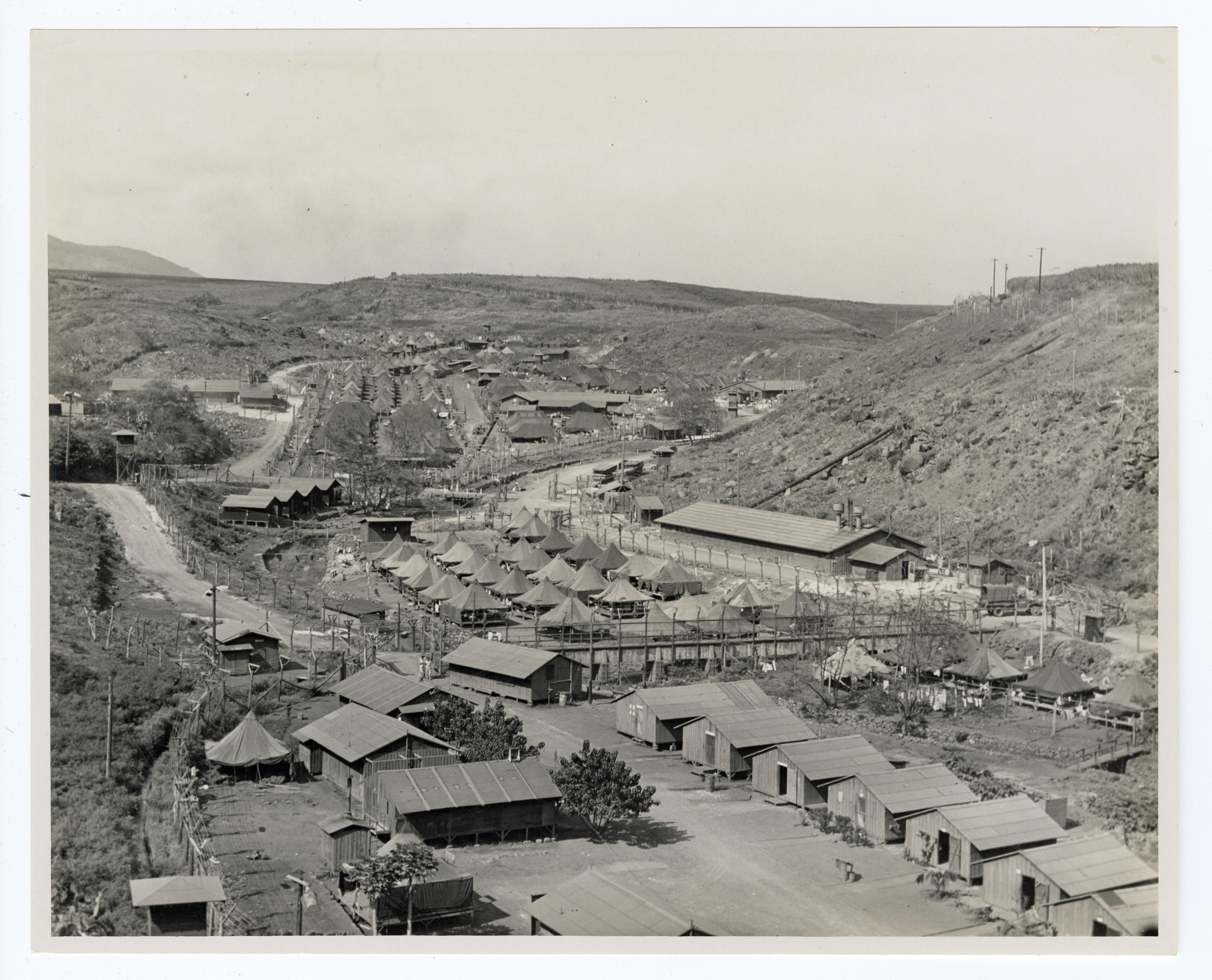 A historic photo of a valley filled with tents and wooden buildings