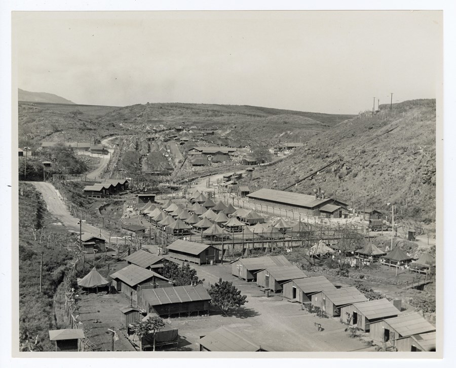 A historic photo of a valley filled with tents and wooden buildings